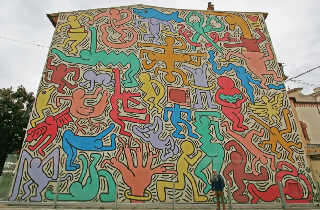 Colorful Tuttomondo mural by Keith Haring on a building in Pisa